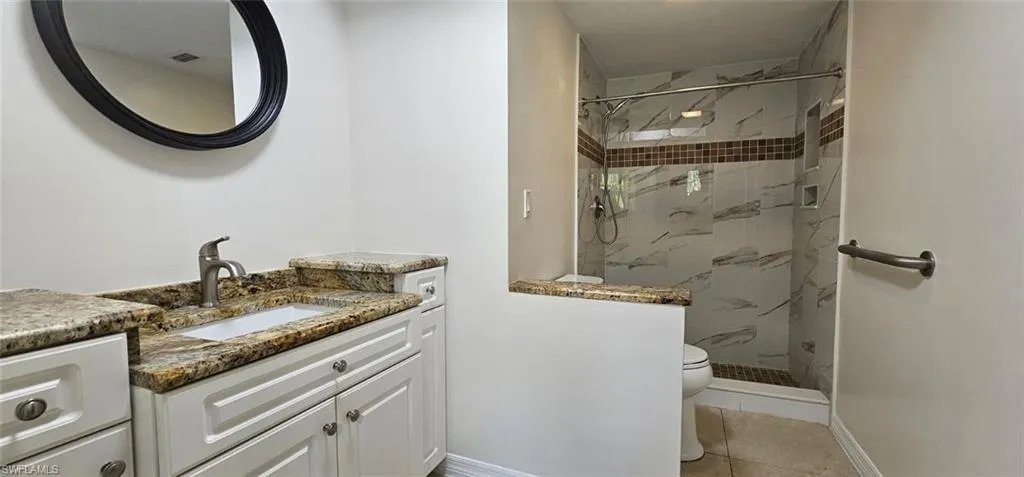 Full bath with vanity, a marble finish shower, and light tile patterned floors