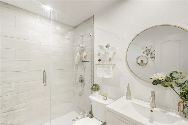 Full bathroom with a textured wall, a stall shower, and vanity
