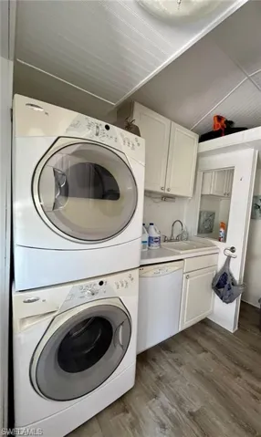 Washroom with stacked washer and clothes dryer and dark wood-style floors