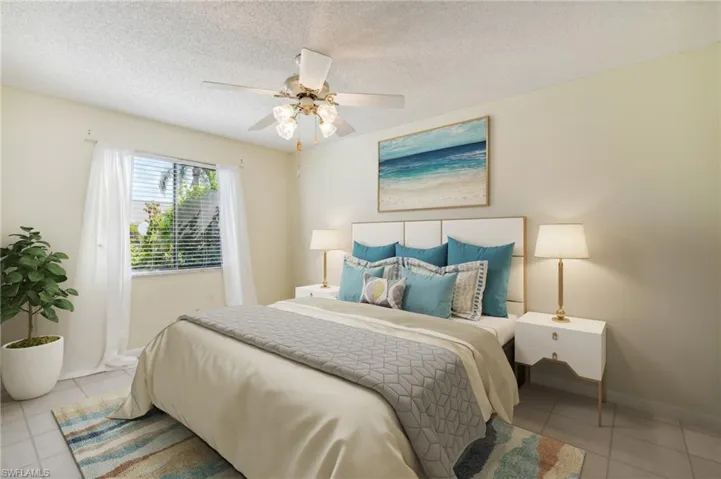 Virtually staged Bedroom featuring tile patterned floors, ceiling fan, baseboards, and a textured ceiling