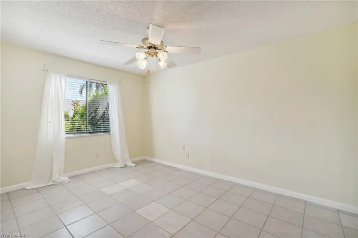 Spare room featuring a textured ceiling, ceiling fan, and light tile patterned flooring