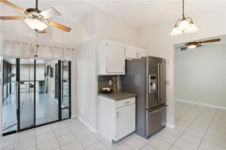 Kitchen with pendant lighting, light tile patterned floors, ceiling fan, high quality fridge, and white cabinets