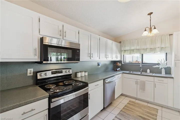Kitchen with tasteful backsplash, white cabinetry, appliances with stainless steel finishes, and sink