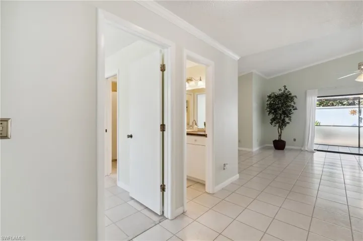 Corridor featuring light tile patterned flooring, a baseboard radiator, crown molding, and a textured ceiling