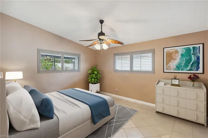 Virtually staged Bedroom featuring multiple windows, light tile patterned floors, baseboards, lofted ceiling, and ceiling fan
