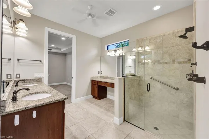 Primary bathroom with double vanity and walk in shower with frameless glass enclosure.