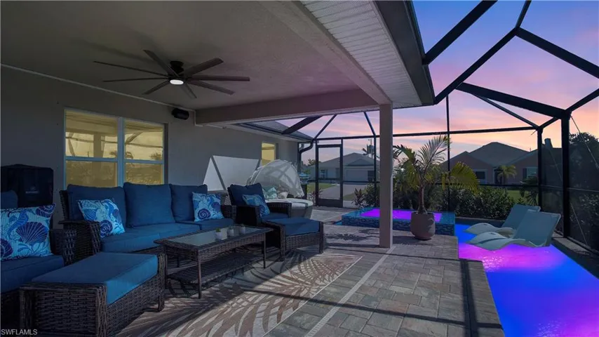 Patio terrace at dusk with ceiling fan, outdoor lounge area, and glass enclosure