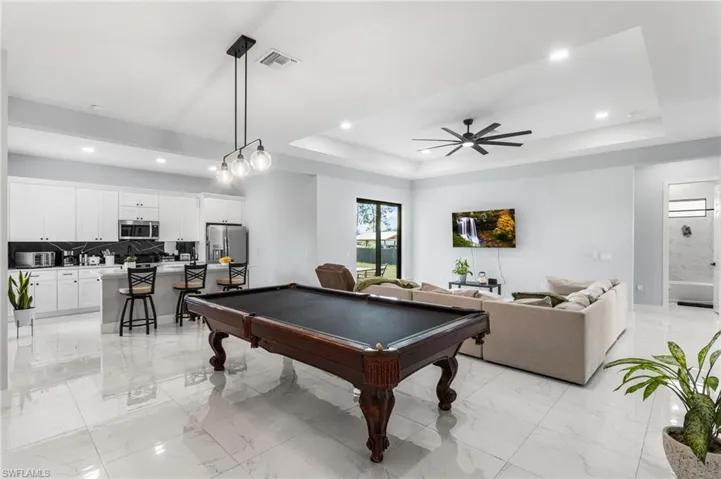 Game room featuring pool table, recessed lighting, a tray ceiling, ceiling fan, and light marble finish flooring