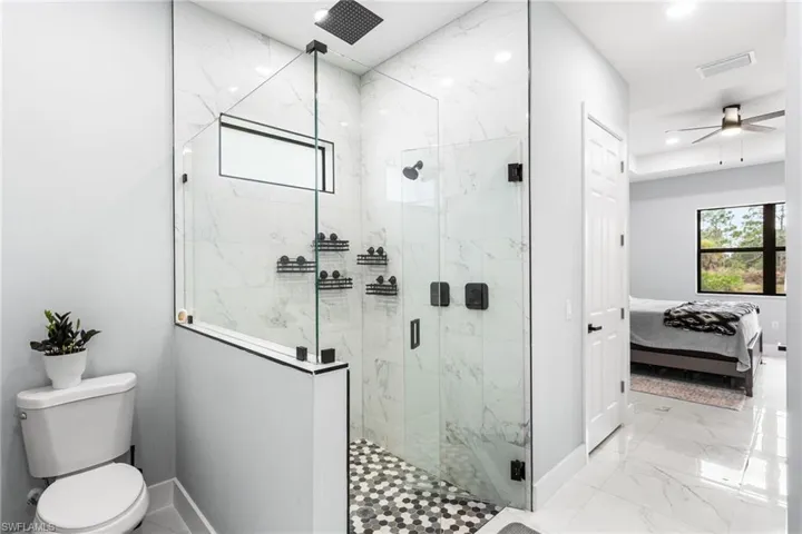 Bathroom with connected bathroom, a marble finish shower, ceiling fan, light marble finish floors, and recessed lighting