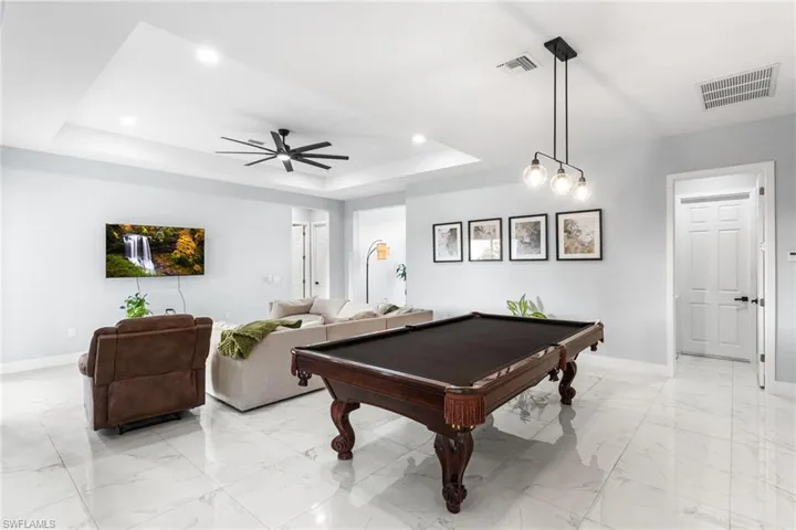 Recreation room featuring ceiling fan, billiards table, recessed lighting, a raised ceiling, and light marble finish floors