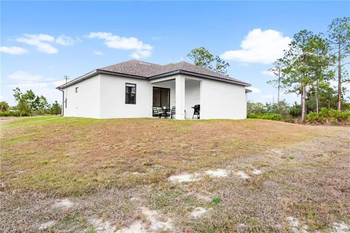 Back of property with stucco siding, a patio, and a lawn
