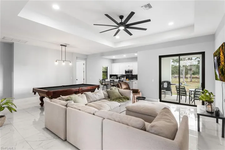 Living room with billiards table, a raised ceiling, plenty of natural light, and recessed lighting