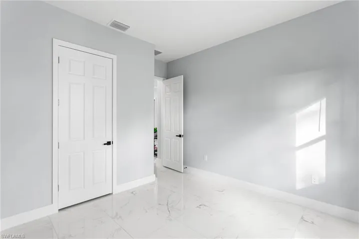 Unfurnished bedroom with baseboards and light marble finish flooring