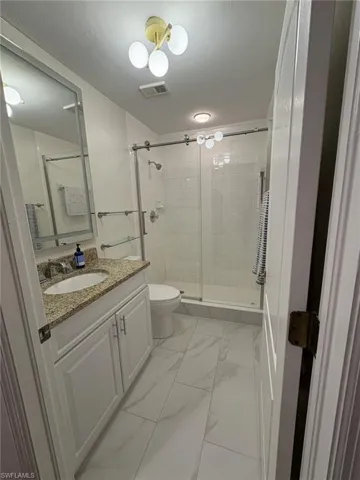 Full bathroom featuring vanity, marble finish flooring, and a shower stall