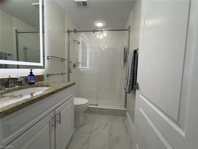 Full bath with vanity, marble look tile flooring, and a stall shower