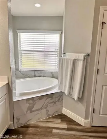 Bathroom featuring a bath, vanity, dark wood-style floors, and recessed lighting