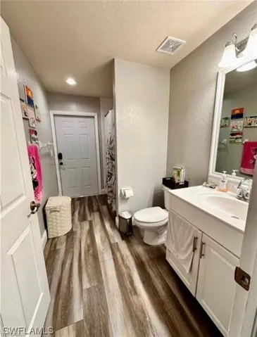 Full bath featuring a textured wall, vanity, a textured ceiling, dark wood finished floors, and a shower with shower curtain