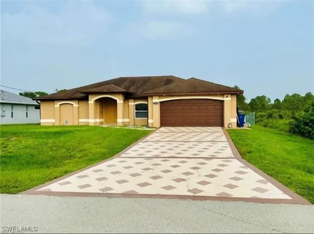 View of front of house featuring driveway, a front lawn, stucco siding, and a garage