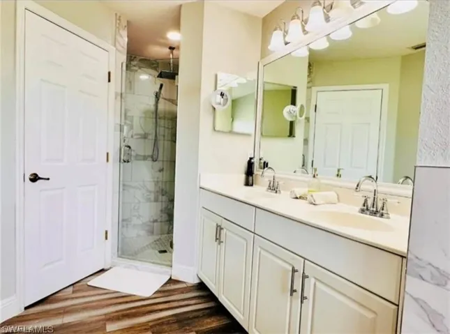 Bathroom featuring a marble finish shower and dark wood-style floors