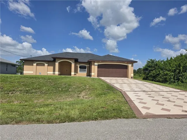 View of front facade with stucco siding, a garage, driveway, and a front lawn