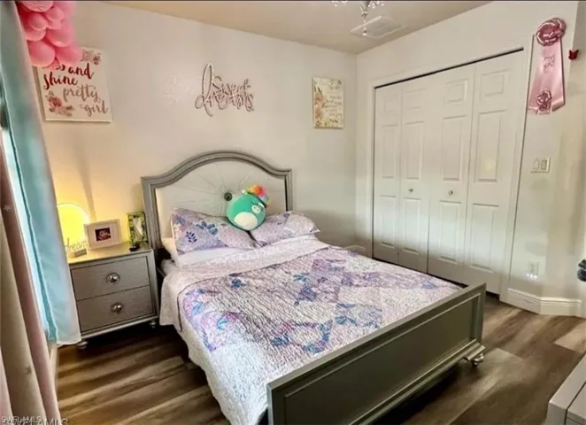 Bedroom with dark wood finished floors and a closet