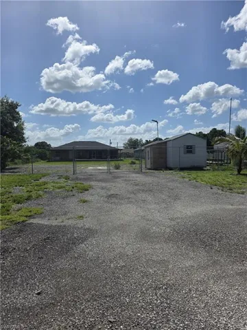 View of yard featuring a carport, gravel driveway, and an outdoor structure