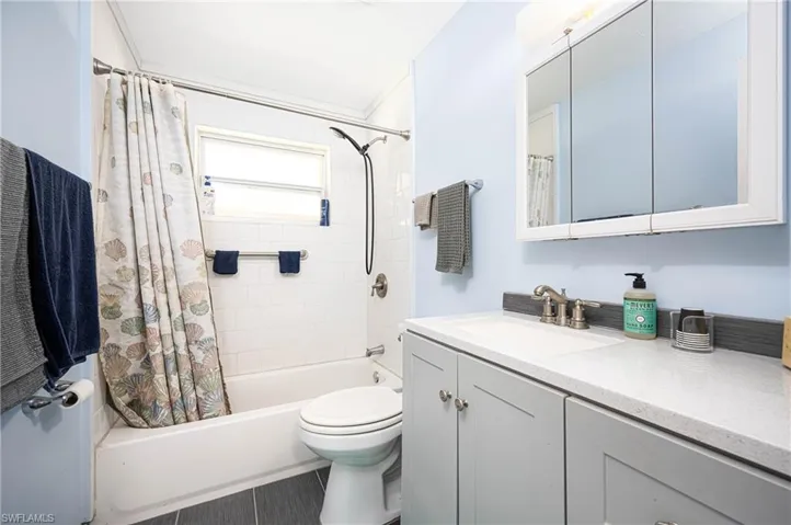 Full bathroom with shower / bathtub combination with curtain, toilet, and vanity