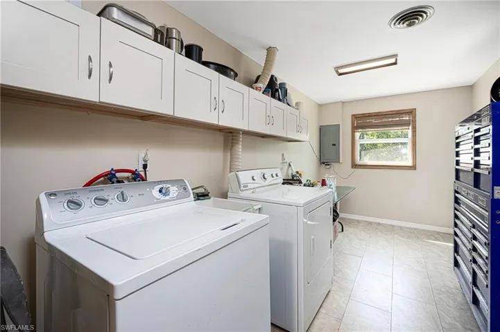 Washroom featuring visible vents, baseboards, washer and clothes dryer, electric panel, and cabinet space