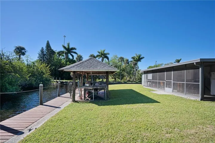 View of yard featuring a dock, a water view, and a sunroom