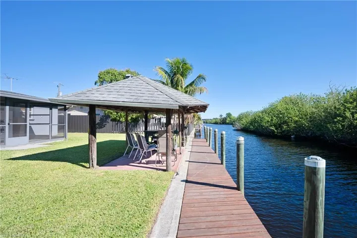 View of dock featuring a gazebo, a yard, fence, and a water view