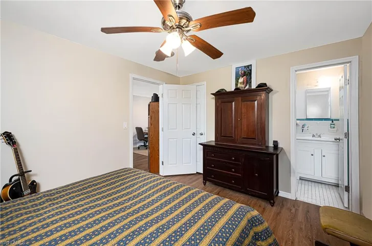 Bedroom featuring ceiling fan, ensuite bath, dark wood finished floors, and a sink