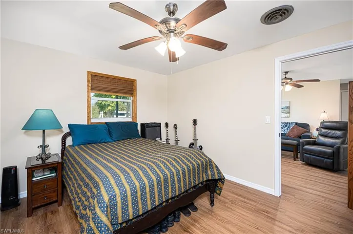 Bedroom featuring visible vents, baseboards, wood finished floors, and a ceiling fan