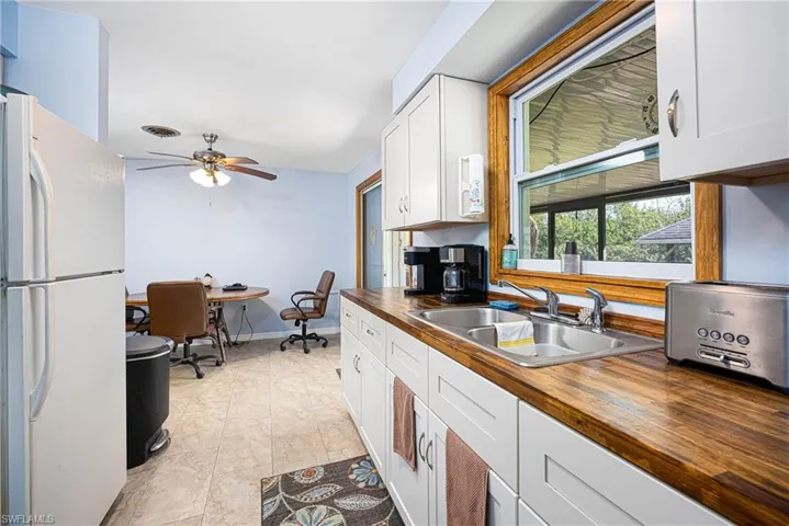 Kitchen with visible vents, butcher block countertops, a ceiling fan, a sink, and freestanding refrigerator