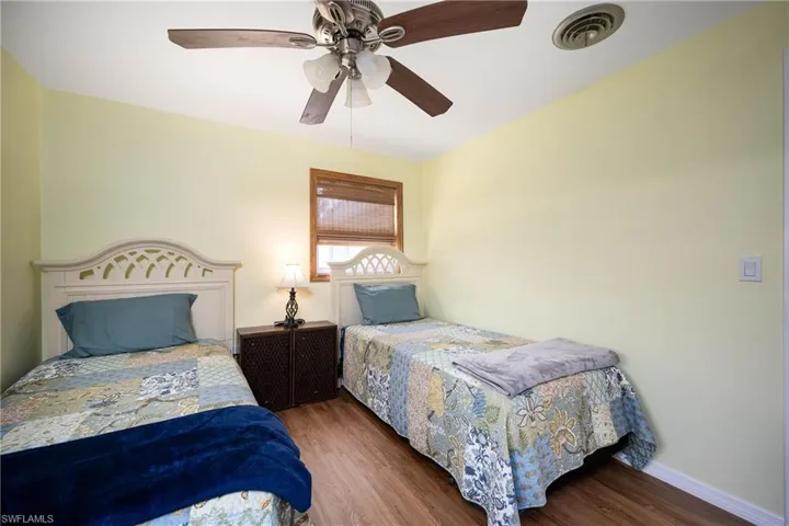 Bedroom with visible vents, a ceiling fan, baseboards, and wood finished floors