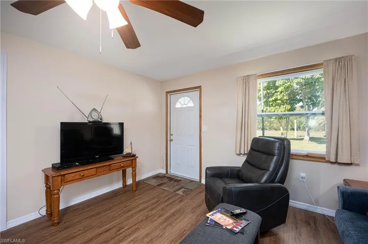 Living area featuring a ceiling fan, wood finished floors, and baseboards