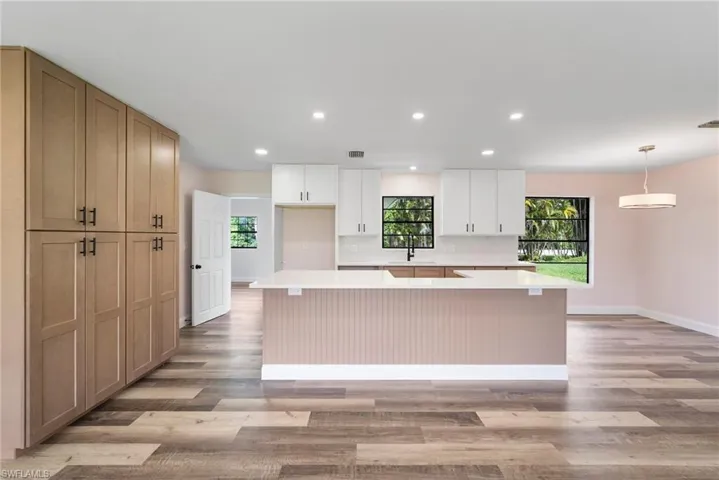Kitchen featuring a center island, decorative light fixtures, backsplash, and light wood-type flooring