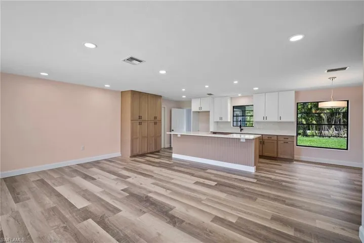 Kitchen featuring pendant lighting, white cabinets, light wood-type flooring, and a kitchen island