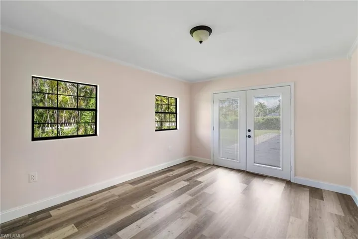 Spare room with light hardwood / wood-style floors, french doors, and ornamental molding