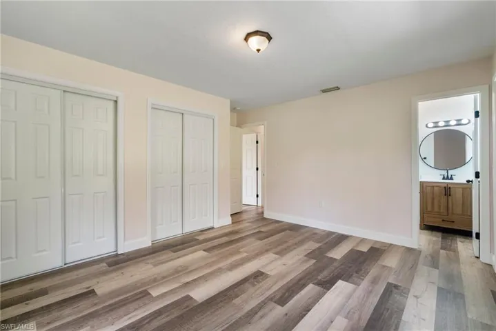 Unfurnished bedroom with sink, multiple closets, wood-type flooring, and connected bathroom