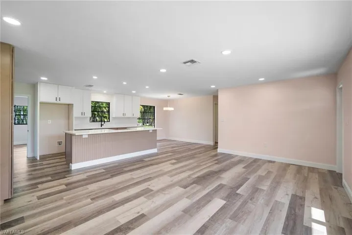 Kitchen with white cabinets, a center island, and light wood-type flooring