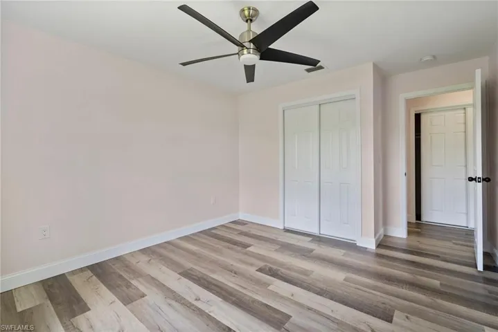 Unfurnished bedroom with ceiling fan, wood-type flooring, and a closet
