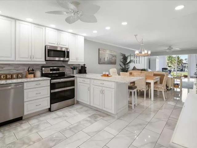 Kitchen featuring a ceiling fan, stainless steel appliances, light stone countertops, a peninsula, and recessed lighting