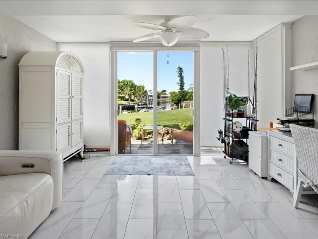 Entryway featuring a textured wall, ceiling fan, a water view, marble look tile flooring, and a wall of windows