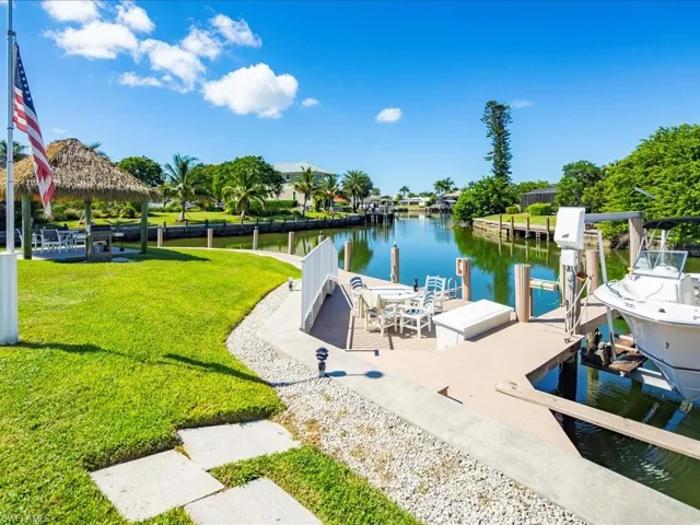 Dock area with a water view, boat lift, a lawn, and a gazebo