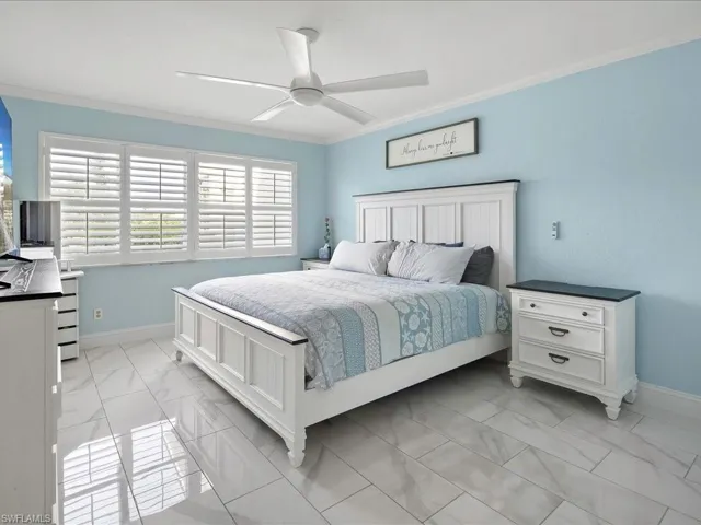 Bedroom with crown molding, a ceiling fan, and light marble finish floors