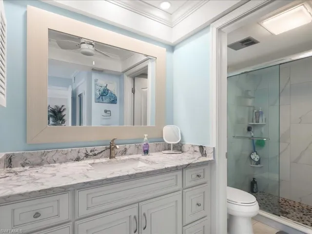 Living area featuring crown molding, light marble finish floors, a ceiling fan, and a chandelier