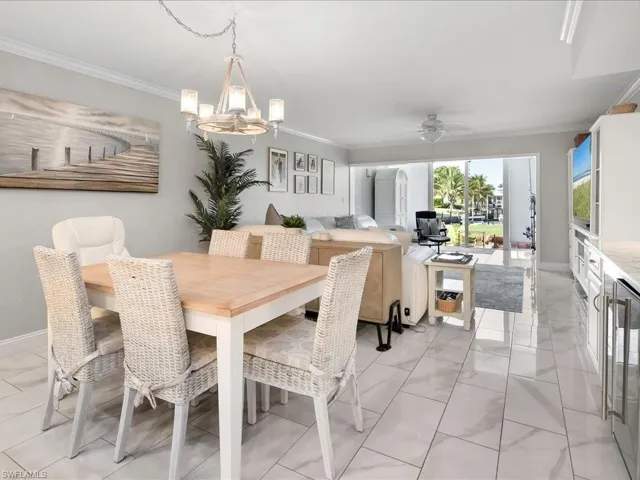 Dining area with ceiling fan, ornamental molding, wine cooler, and a chandelier