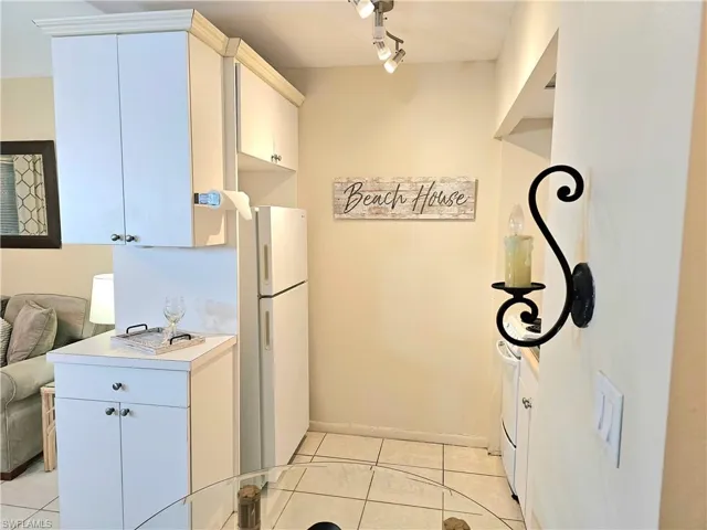 Kitchen featuring white refrigerator, track lighting, and light tile floors