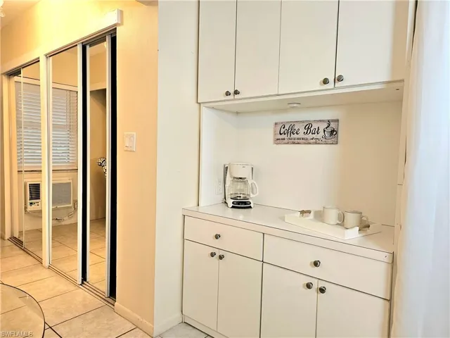 Bar featuring white cabinets and light tile flooring