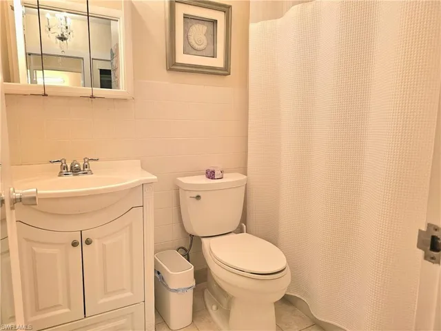 Bathroom featuring tile flooring, oversized vanity, tile walls, backsplash, and toilet
